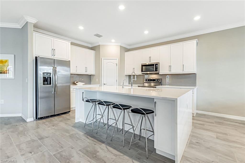 1603 Santiago Circle Naples, FL 34113 - Photo 21 of 46 a kitchen with kitchen island granite countertop a stove refrigerator and microwave