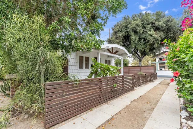 a view of a wooden house with a large tree and wooden fence