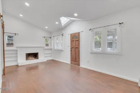 an empty room with windows and fireplace