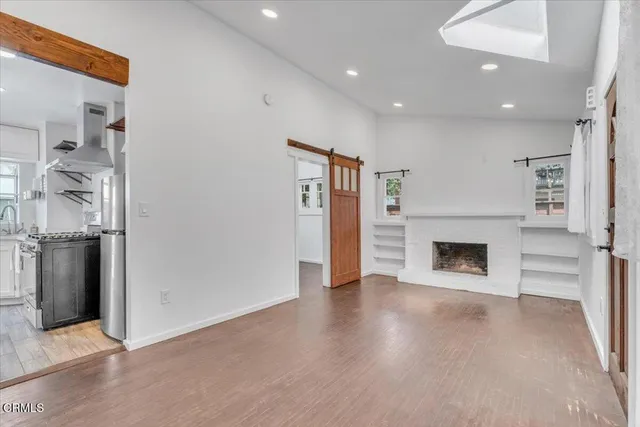 an empty room with wooden floor fireplace and windows