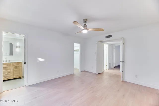an empty room with chandelier fan and windows
