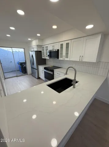 a kitchen with stainless steel appliances a sink a stove a refrigerator a center island and couches