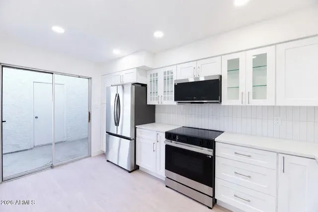 a kitchen with stainless steel appliances white cabinets and a refrigerator
