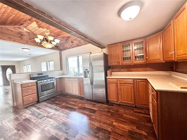 a kitchen with granite countertop a sink cabinets stainless steel appliances and a window