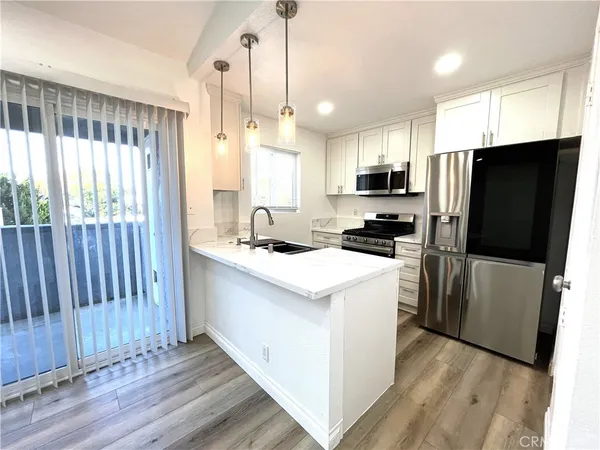 a kitchen with a refrigerator a microwave a sink and wooden floor
