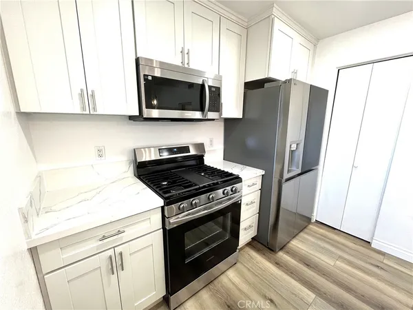 a kitchen with stainless steel appliances white cabinets a stove a microwave and a refrigerator