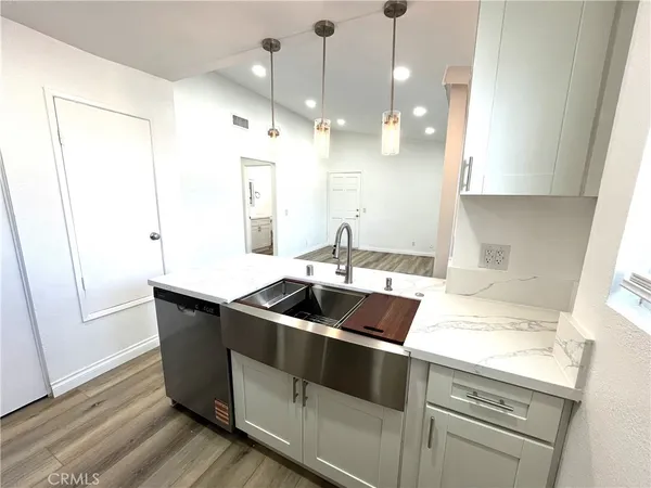 a kitchen with granite countertop a sink a counter space appliances and cabinets
