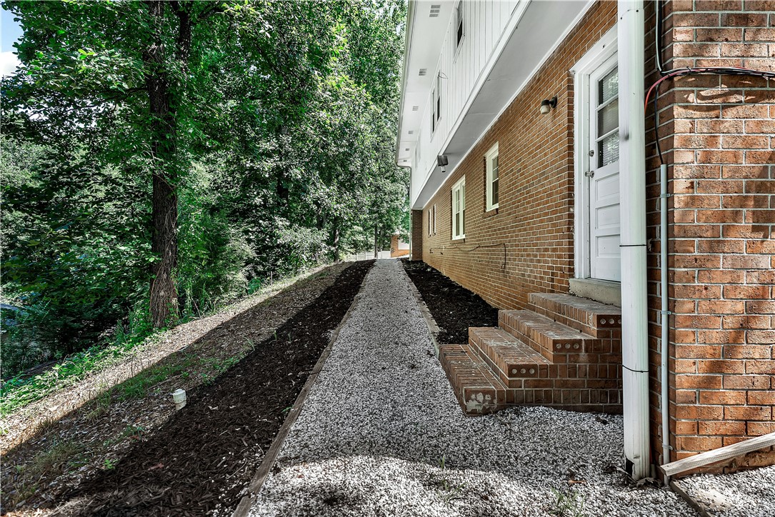 2011 Forest Drive Seneca, SC 29672 - Photo 6 of 36 A private side entry features brick steps leading to the home, set against a backdrop of mature trees and landscaping.