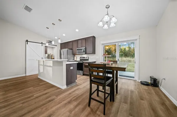 a kitchen with stainless steel appliances a dining table chairs stove and refrigerator