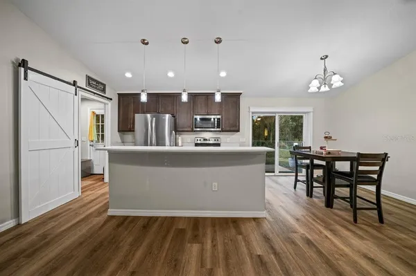a living room with stainless steel appliances kitchen island granite countertop furniture wooden floor and a kitchen view