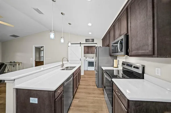 a large kitchen with stainless steel appliances a sink a stove and a refrigerator