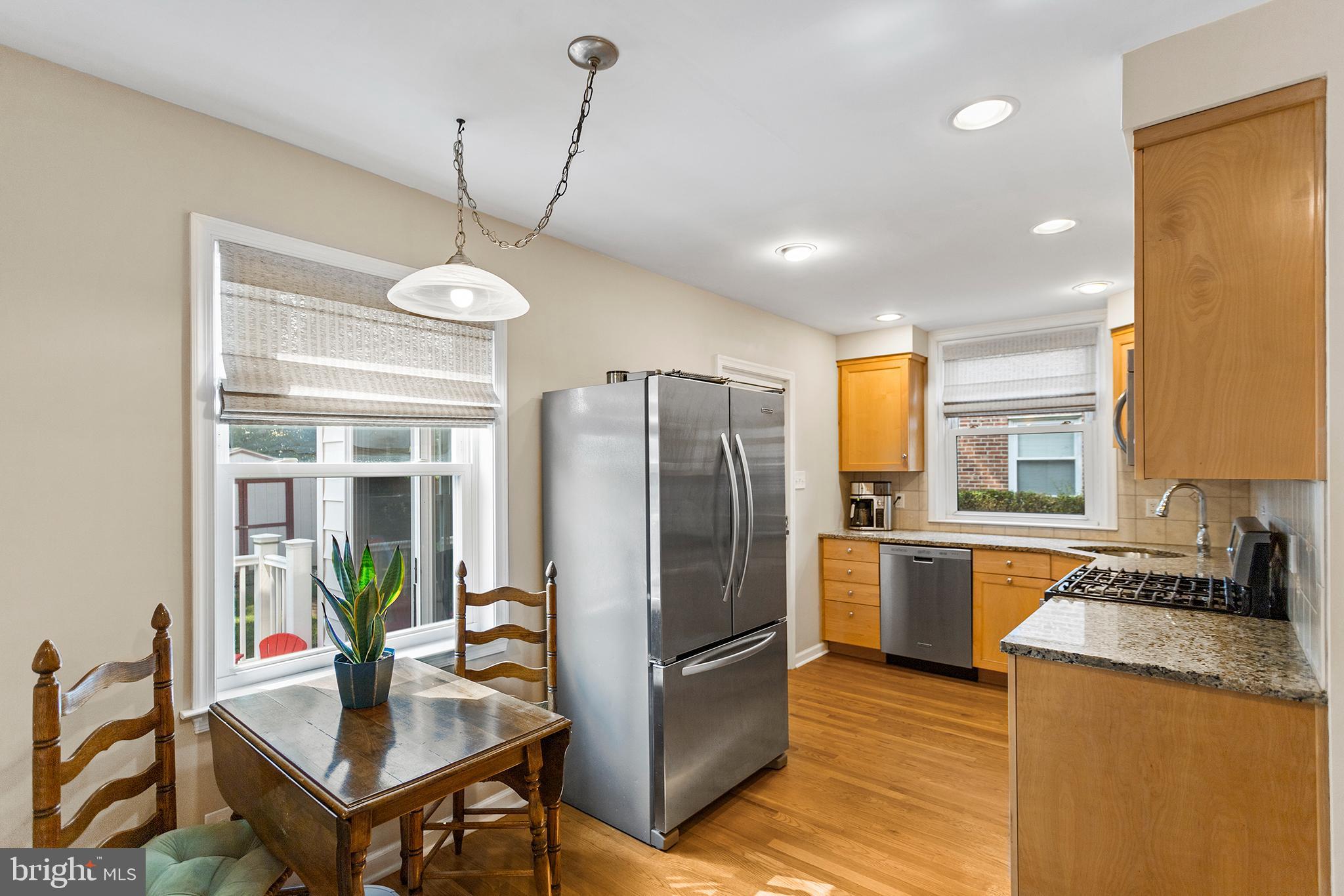 1806 Earlington Road Havertown, PA 19083 - Photo 7 of 27 a kitchen with stainless steel appliances granite countertop a refrigerator a sink dishwasher a stove and a dining table with wooden floor