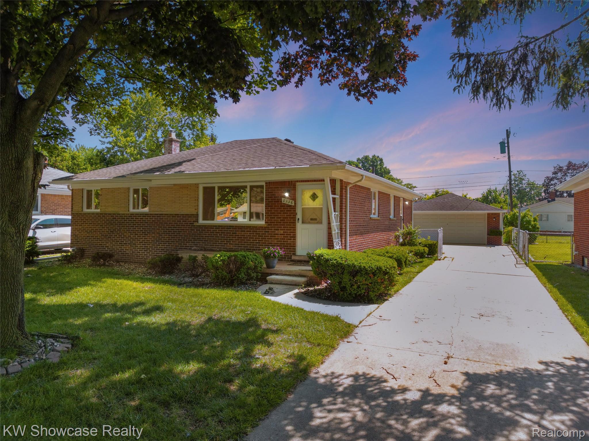 8936 Merriman Road Livonia, MI 48150 - Photo 2 of 49 Brick exterior with a detached garage, a concrete driveway, a manicured lawn, and established landscaping