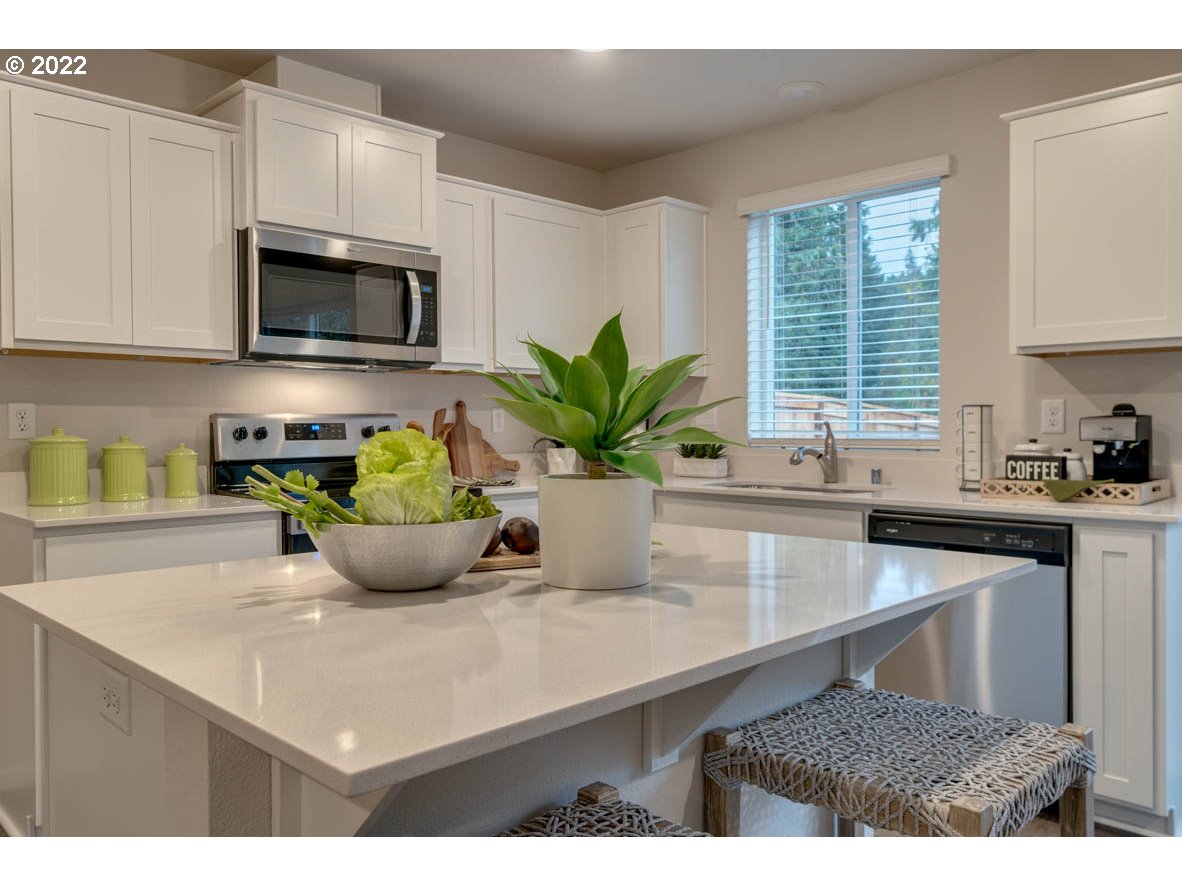 218 North Layla Place Ridgefield, WA 98642 - Photo 8 of 38 a kitchen with a sink a potted plant and cabinets