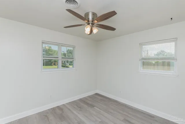 an empty room with a window and ceiling fan