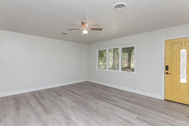 an empty room with wooden floor and windows