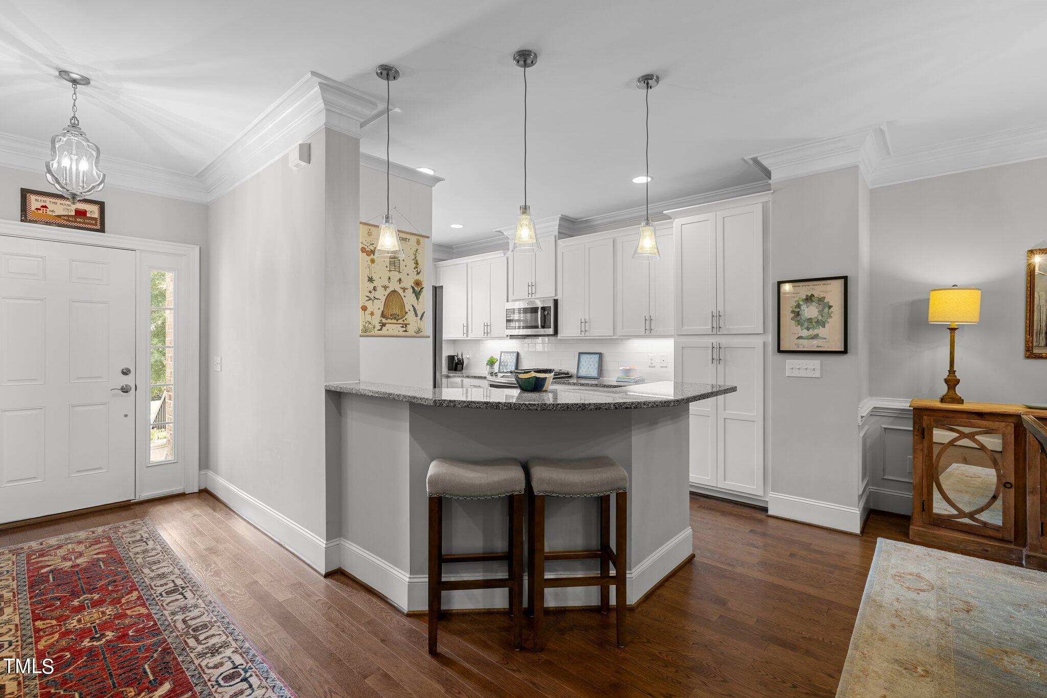 504 Valleyshire Road Durham, NC 27707 - Photo 13 of 38 a kitchen with kitchen island granite countertop a sink cabinets and wooden floor