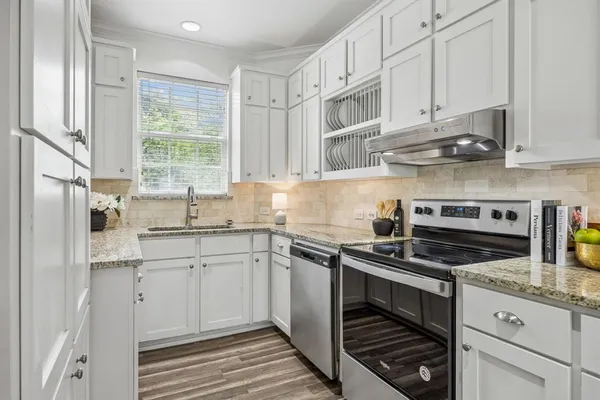 a kitchen with stainless steel appliances granite countertop white cabinets and a sink