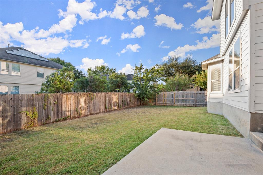 10105 Wind Cave Trail Austin, TX 78747 - Photo 22 of 23 Expansive backyard featuring a manicured lawn, full privacy fencing, and a concrete patio pad