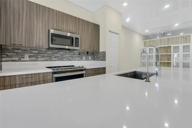 a kitchen with stainless steel appliances a stove sink microwave and cabinets