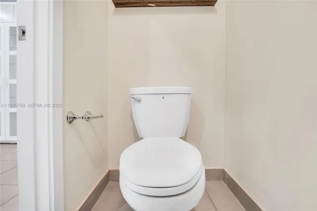 a white toilet sitting next to a white wall