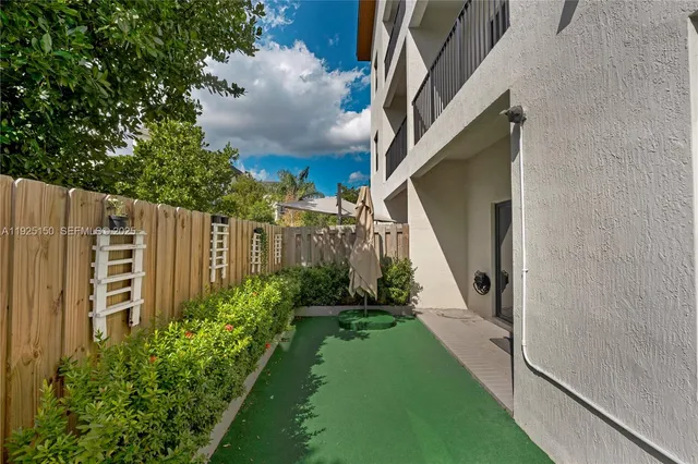 a view of a pathway of a house with flower plants and wooden fence