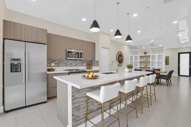 a kitchen with stainless steel appliances kitchen island granite countertop a table chairs and a refrigerator