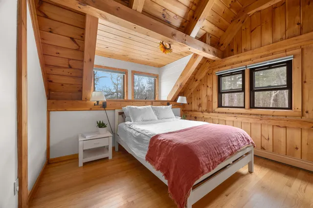 a bedroom with a bed a mirror and a wooden floor