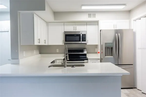 a kitchen with stainless steel appliances a refrigerator a stove and white cabinets
