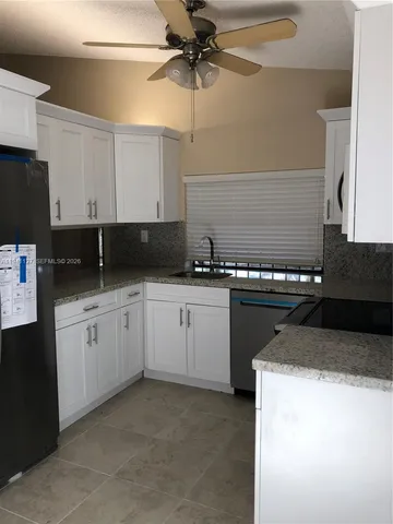 a kitchen with granite countertop a sink a stove and cabinets
