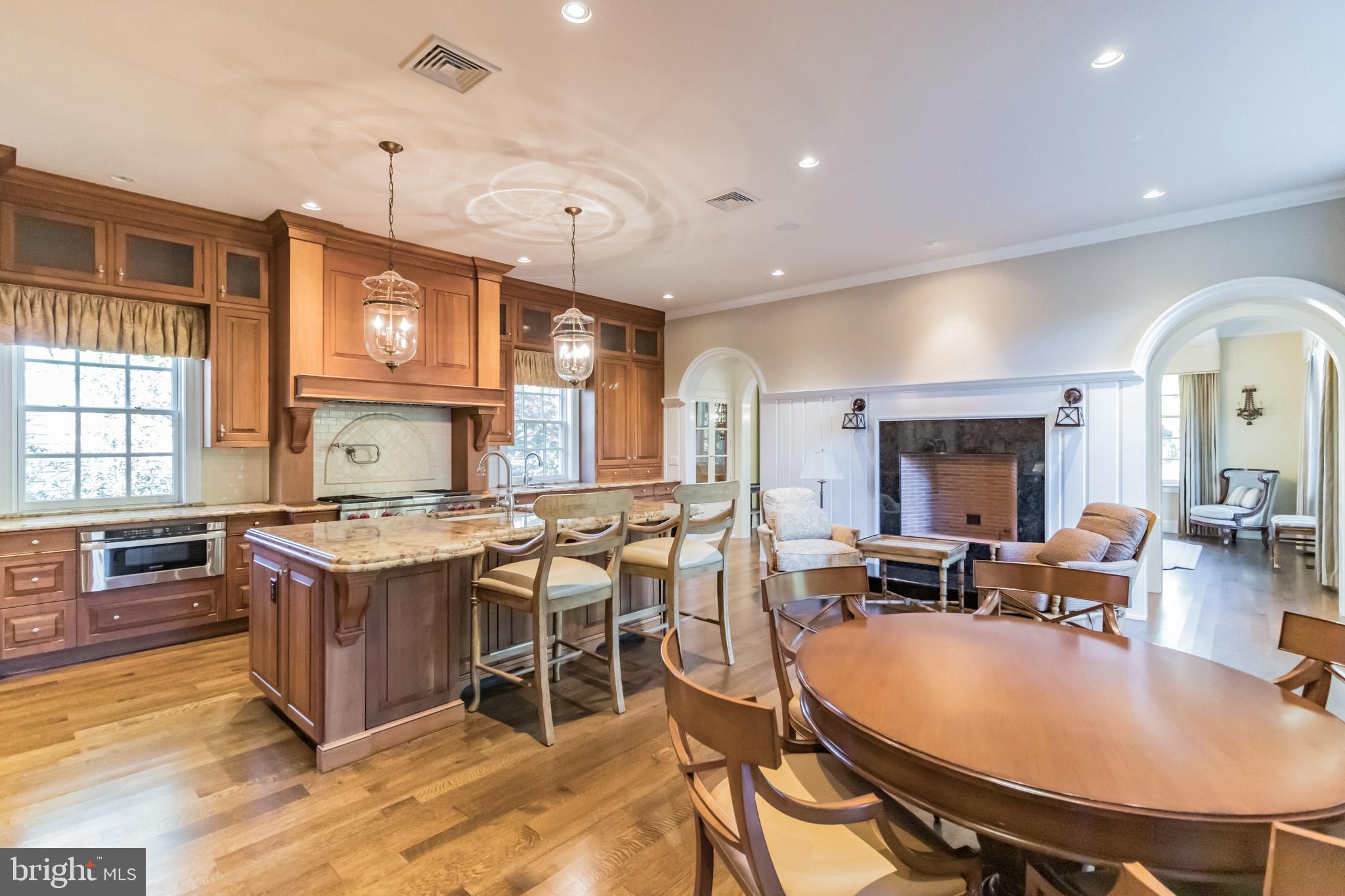 1911 Stone Ridge Lane Villanova, PA 19085 - Photo 13 of 32 a open kitchen with stainless steel appliances granite countertop a stove a refrigerator dining table and chairs with wooden floor
