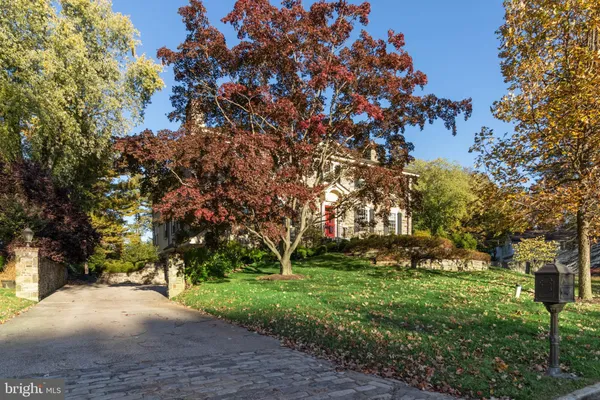 a view of a brick house next to a yard with big trees