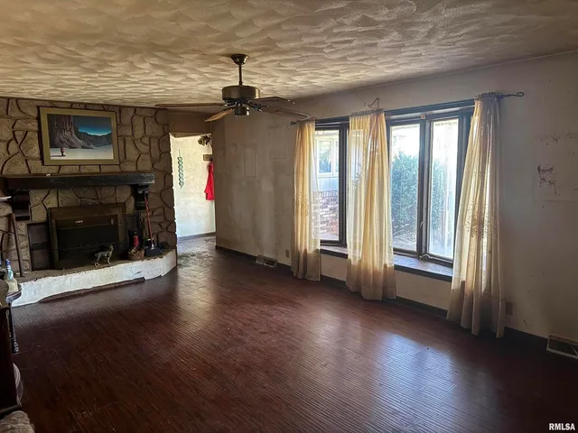 an empty room with wooden floor fireplace and windows