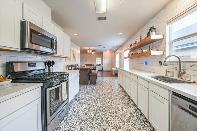 a large kitchen with stainless steel appliances granite countertop a stove a sink dishwasher and a microwave oven with large wooden cabinets