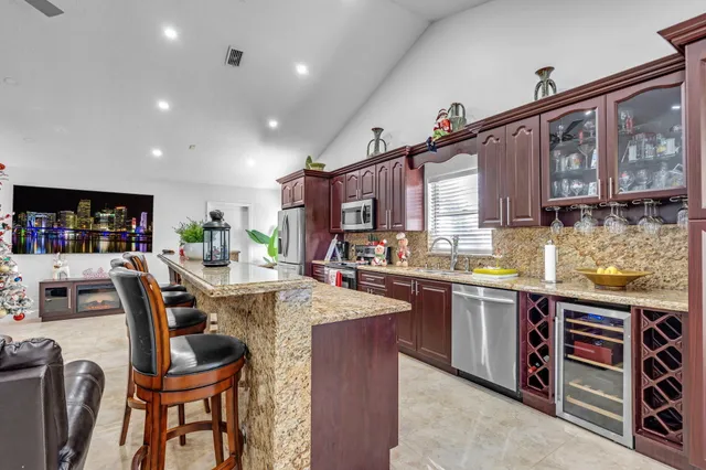 a kitchen with stainless steel appliances granite countertop a refrigerator a stove a sink a dining table and chairs