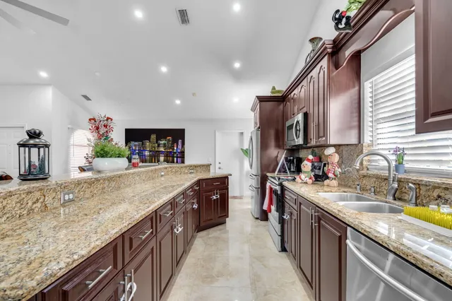 a kitchen with kitchen island granite countertop a sink counter top space and stainless steel appliances