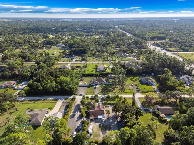 an aerial view of residential houses with outdoor space and trees