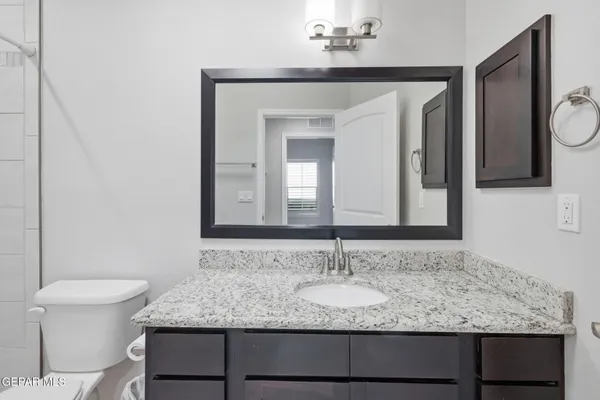 a bathroom with a granite countertop sink a mirror and a bathtub