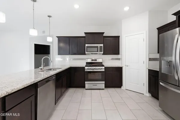 a kitchen with granite countertop a refrigerator and a stove top oven