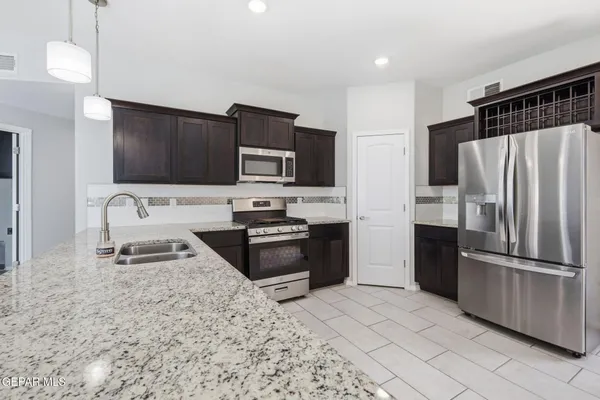 a large kitchen with stainless steel appliances granite countertop a stove a sink and a microwave