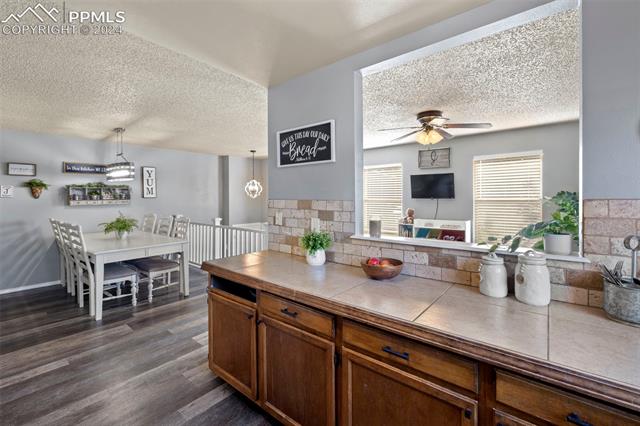 1830 Doherty Road Colorado Springs, CO 80916 - Photo 13 of 34 Kitchen with ceiling fan, decorative light fixtures, dark hardwood / wood-style flooring, a textured ceiling, and tile countertops