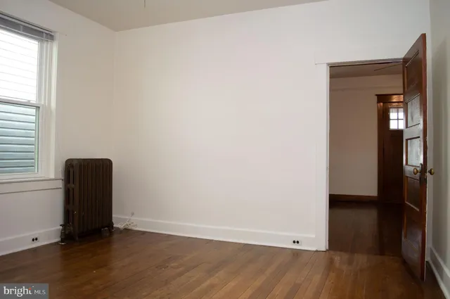 an empty room with wooden floor and a window