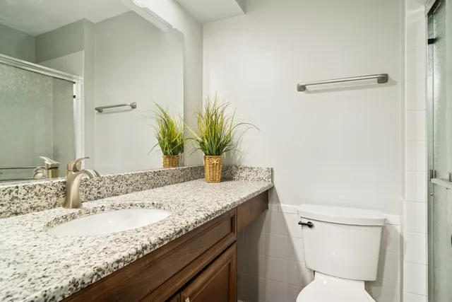 a bathroom with a granite countertop sink a toilet and a mirror