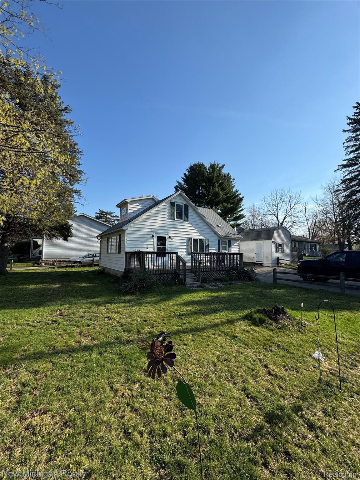 305 East Rolfe Street Perry, MI 48872 - Photo 1 of 19 View of property exterior featuring a lawn and a deck