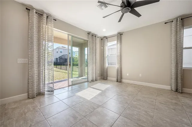 a view of an empty room with wooden floor kitchen view and a window
