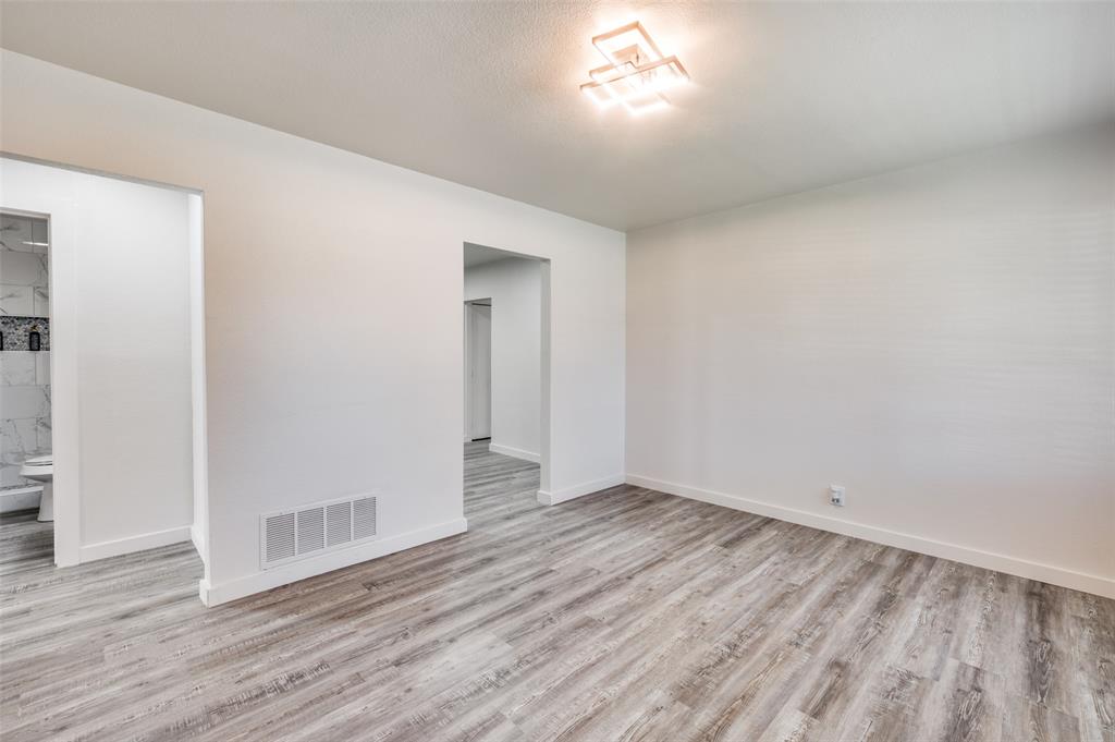 733 Southeast 3rd Street Grand Prairie, TX 75051 - Photo 11 of 24 Empty room with light wood-type flooring and a textured ceiling