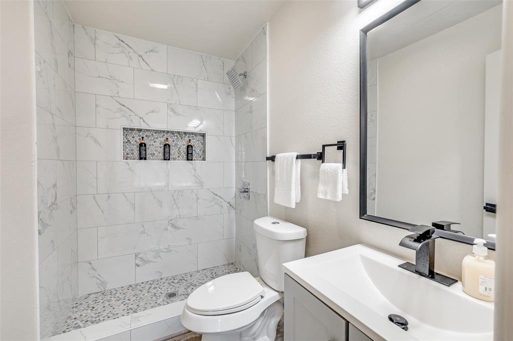 733 Southeast 3rd Street Grand Prairie, TX 75051 - Photo 13 of 24 Bathroom with vanity, a textured wall, and a tile shower