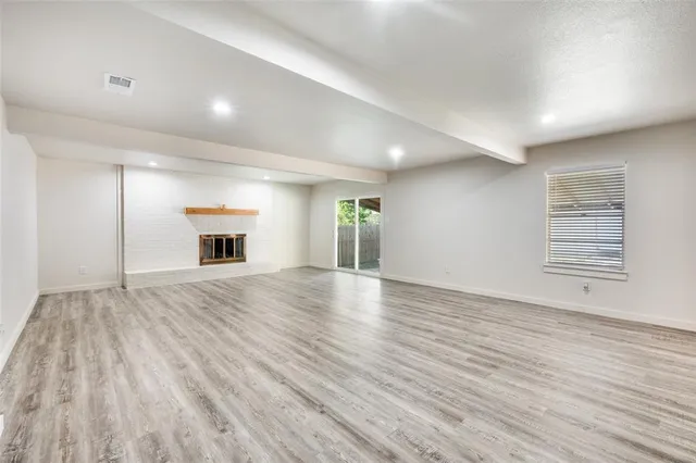 a view of empty room with wooden floor and fireplace
