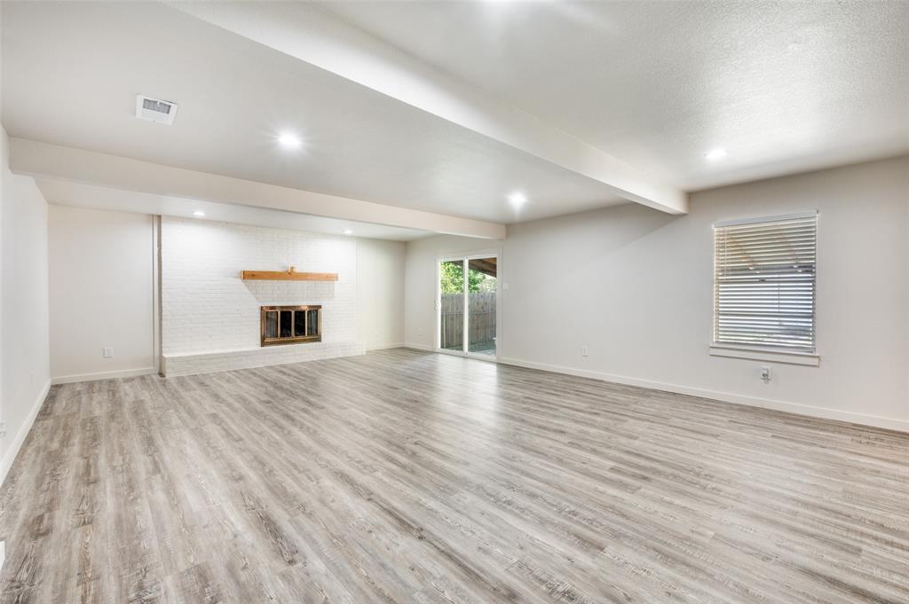 733 Southeast 3rd Street Grand Prairie, TX 75051 - Photo 5 of 24 Unfurnished living room with beam ceiling, light wood-type flooring, a brick fireplace, and recessed lighting