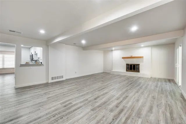 an empty room with wooden floor and a kitchen